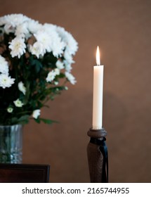Funeral lit candle with black ribbon next to the coffin. Sad moment for the family. White candle during memorial service with wide black ribbon around it - Shutterstock ID 2165744955