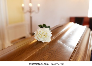 Funeral And Mourning Concept - White Rose Flower On Wooden Coffin In Church