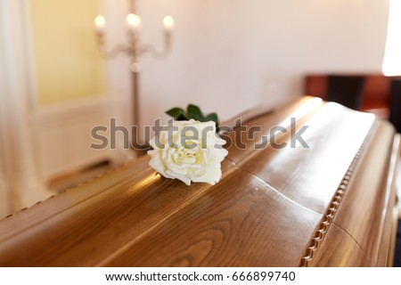 funeral and mourning concept - white rose flower on wooden coffin in church