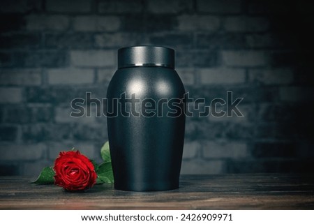 Funeral mourning urn next to a rose flower.