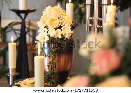 A funeral urn stands with lit candles in a cemetery chapel just before the funeral service.