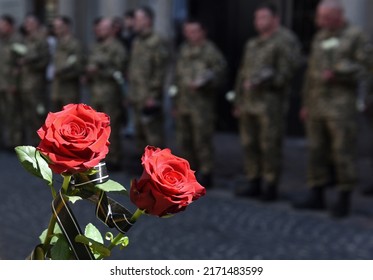 A funerals of Ukrainian servicemen killed during Russia's invasion of Ukraine. Soldier holds flowers - Shutterstock ID 2171483599