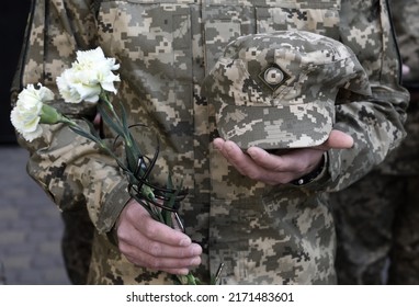 A funerals of Ukrainian servicemen killed during Russia's invasion of Ukraine. Soldier holds flowers - Shutterstock ID 2171483601