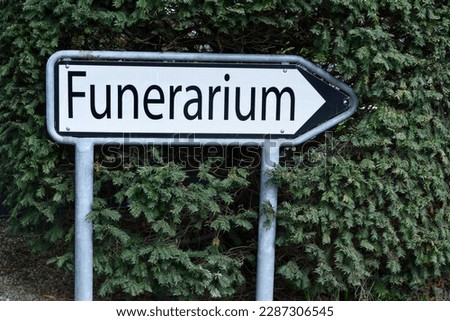 a funerarium sign located in a green garden.
