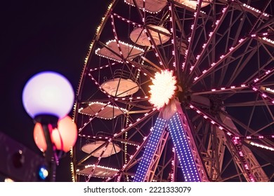 Funfair ferris wheel at night. Ferris wheel and rollercoaster in motion at amusement park at night
