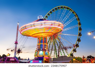 Funfair panorama wiht ferris wheel and carousels on big german funfair “Cranger Kirmes“ in Herne at blue hour twilight. Long time exposure with multi color light traces (“Kasse“ means cash register). - Powered by Shutterstock