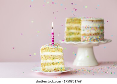 Funfetti Birthday Layer Cake With One Candle And A Single Slice Removed Against A Pink Background