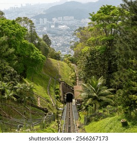 Funicular railway on Penang Hill, track leading into tunnel surrounded by lush greenery, tropical plants, vibrant forest, scenic hillside, travel destination, adventure, tourism attraction - Powered by Shutterstock