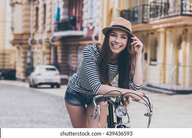 Funky beauty.  Beautiful young woman leaning at her bicycle and smiling while standing outdoors - Powered by Shutterstock