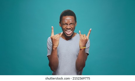 Funky Cool Man Showing Rock Metal Sign With Hands In Front Of Camera, Expressing Fun Punk Music With Positive Energy. Male Hipster Rocker Gesturing Devil Horns Symbol For Entertainment.