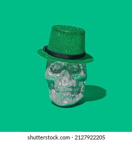 Funky death-s-head minimal concept. Silver glitter skull with green top of hat on it. Nice green background.