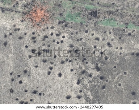Funnels from artillery explosions cannon shells on the ground: top view drone shot. Ground Surface is covered with shell funnel explosions - Ukrainian territory during the Russian-Ukrainian war.