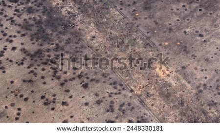 Funnels from artillery explosions cannon shells on the ground: aerial drone shot of destroyed burnt military equipment on Shelled ground and defensive positions during the Russian-Ukrainian war.