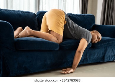Funny action drunk hangover people resting on Couch after party. Unhappy asian man headache Upset frustrated by problem love relationship feeling despair and anxiety Depressed and Stressed asian man