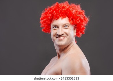 funny adult man in an orange curly wig with facial expressions on a dark background - Powered by Shutterstock