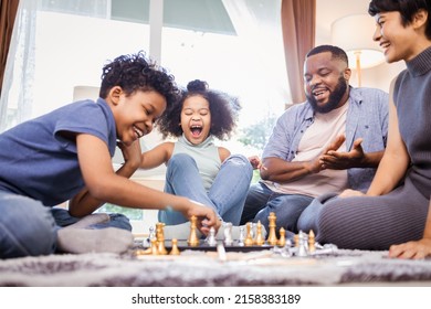 Funny African American children playing chess with mom and dad at home - Powered by Shutterstock