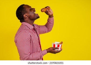 funny african american man eating fried chicken leg in studio yellow background - Shutterstock ID 2195821051