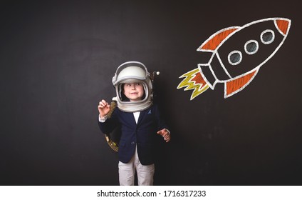 Funny amazed child playing pilot. Happy little boy and rocket isolated on black - Powered by Shutterstock