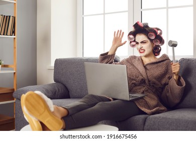Funny angry vexed woman sitting on sofa at home, suffering from software problem, slow website or bad wifi, reading negative hater comment, holding meat hammer, threatening to destroy laptop computer
