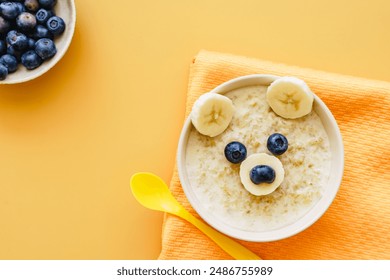 Funny animal face on baby porridge in a bowl. Top view, yellow background, colorful, breakfast. - Powered by Shutterstock