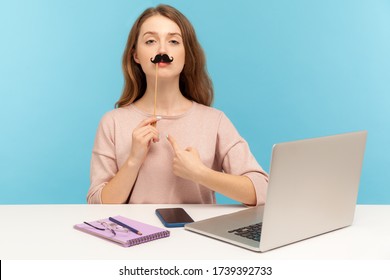 Funny Arrogant Woman Office Employee Pointing Herself, Covering Lips With Fake Paper Moustache, Imitating Strict Boss, Humorous Masquerade Accessory. Indoor Studio Shot Isolated On Blue Background