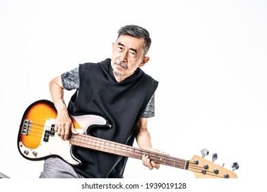 A Funny Asian Elder Cool Man Has Fashion In Gray T-shirt And Black Vest Play Bass Guitar. Shoot On White Background In The Studio. Positive Active Old Cool Senior Healthy Retirement Concept.