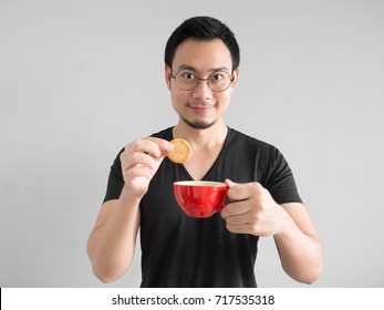 Funny Asian man showing how to eat cookies in a happy way.