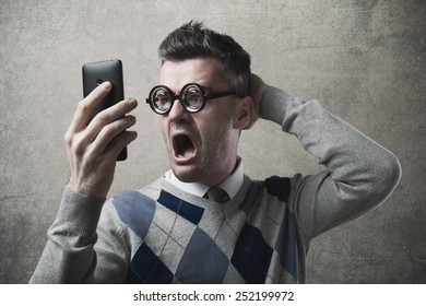 Funny astonished angry guy having troubles with his smartphone