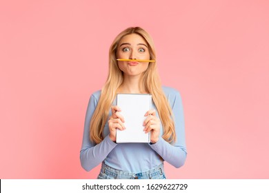 Funny Attractive Female Student Keeping Pencil Between Nose And Lips As Moustache, Holding Notebook, Copyspace