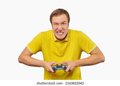 Funny attractive gamer in yellow T-shirt with gamepad isolated on white background. Cheerful young guy holding joy stick and playing videogames on TV, excited video game player