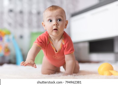 Funny baby boy crawling on the floor in nursery room
