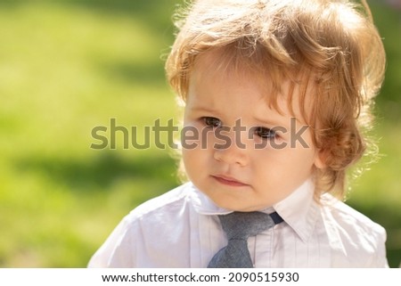 Funny baby child face. Outdoor portrait of cute little boy in suit and necktie tie. Little businessman.
