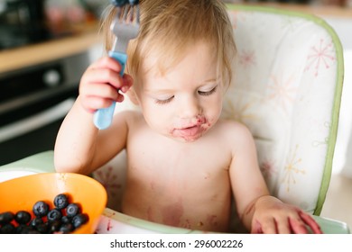 Funny Baby Eating Blueberries For The Breakfast. She Is Dirty With The Berries