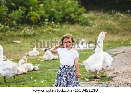 Funny baby girl with goose in a roud on a beautiful sunny autumn