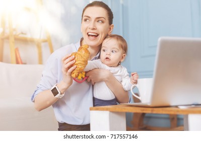 Funny baby girl looking at croissant - Shutterstock ID 717557146