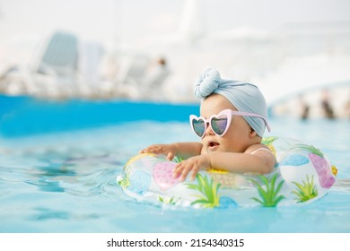 Funny Baby Girl On Summer Vacation. Child Having Fun In Swimming Pool. Sweet Toddler Swimming In A Floating Ring In A Pool. Water Park. Holidays.