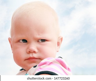 Funny baby girl outdoor summer close up portrait above cloudy sky