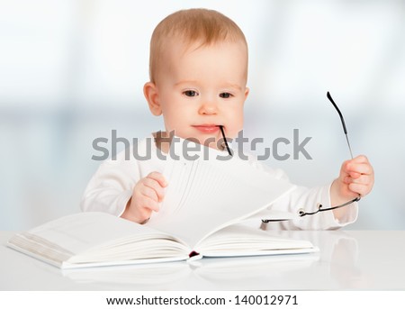 funny baby with glasses reading a book