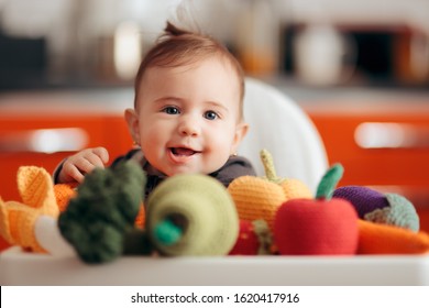 Funny Baby With Knitted Vegetables Starting Food Diversification. Cute Adorable Child Playing With Handmade Crochet Toys
