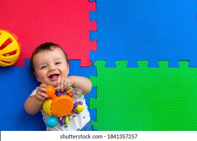 Funny baby playing on colorful eva rubber floor. Toddler having fun indoor his home. Top view.