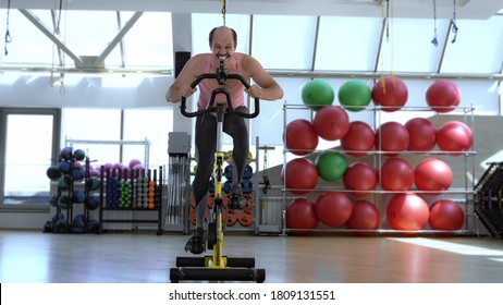 funny bald man is training on an exercise bike, smiling. full height