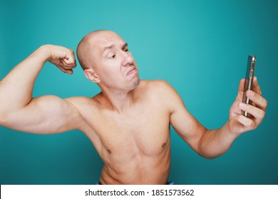 A Funny Bald And Naked Man With Emotions Holds Mobile Phone And Taking Selfie With Him Muscle Arm