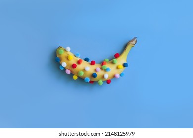 Funny banana with pom-poms, banana pasted over with round colored pom-poms, strange fruit concept