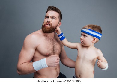 Funny Bearded Dad And His Son Playing And Fighting Over Grey Background