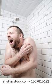 Funny bearded man feels shocked by taking a cold shower, he froze, screams and tries to close his body with hands.
