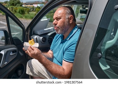 Funny Bearded Middle Aged Man Eating Vegan Sandwich On The Street Near The Car. Unhealthy Eating. Fast Food. Takeaway Food