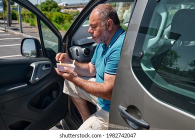 Funny Bearded Middle Aged Man Eating Vegan Sandwich On The Street Near The Car. Unhealthy Eating. Fast Food. Takeaway Food