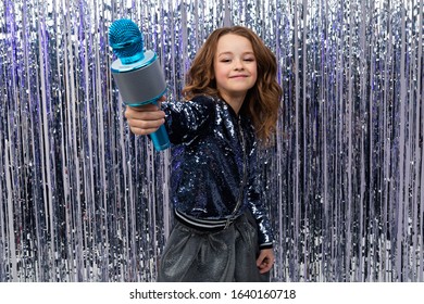 Funny Beautiful Holiday Host Holds Out A Microphone And Shows The Class Against A Background Of Shiny Tinsel