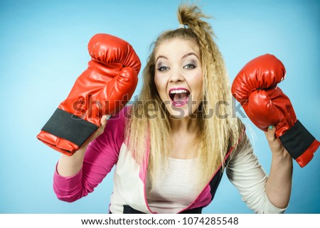 Funny blonde girl female boxer in big fun red gloves playing sports boxing studio shot on blue