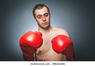 Funny Boxer Man With Closed Eyes In Knockout Over Dark Gray Background. Comic Weak Fighter With Red Sport Boxing Gloves. Waist Up Humorous Kickboxer